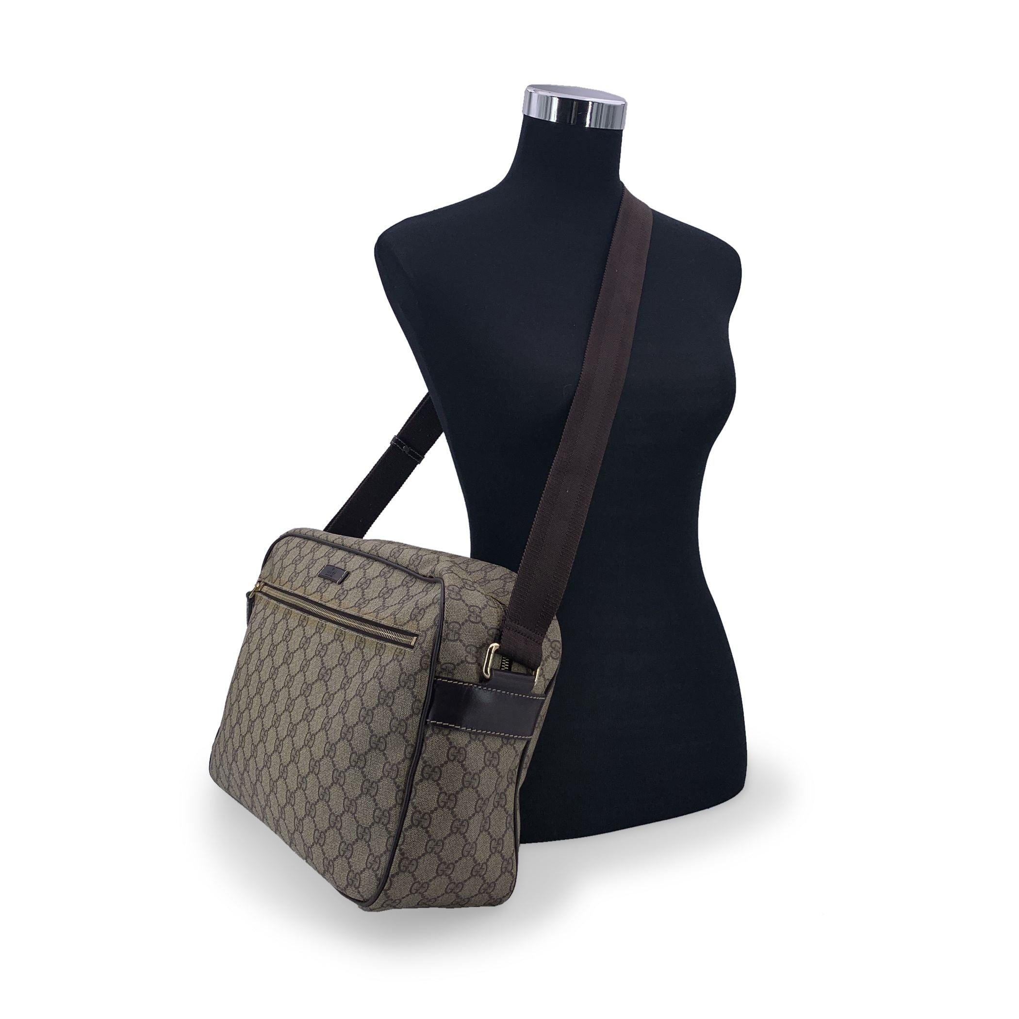 Practical Gucci GG Monogram Supreme canvas large camera messenger bag . The bag features beige and ebony monogram canvas. Front zip pocket. Upper zipper closure. Adjustable shoulder strap. Brown fabric lining. 1 open pocket inside. 'Gucci - Made in