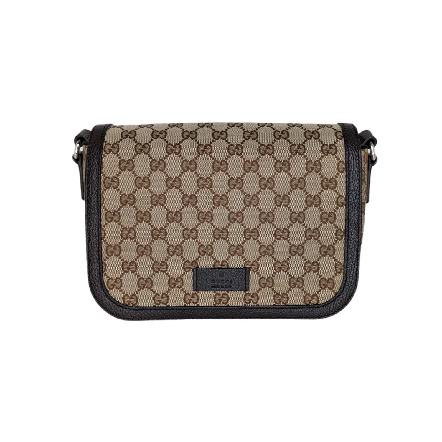 This stylish messenger bag is crafted of classic dark brown on beige Gucci GG monogram canvas. The bag features a complementary chocolate brown leather trim and an adjustable fabric body strap with silver-tone hardware. The flap opens to a chocolate