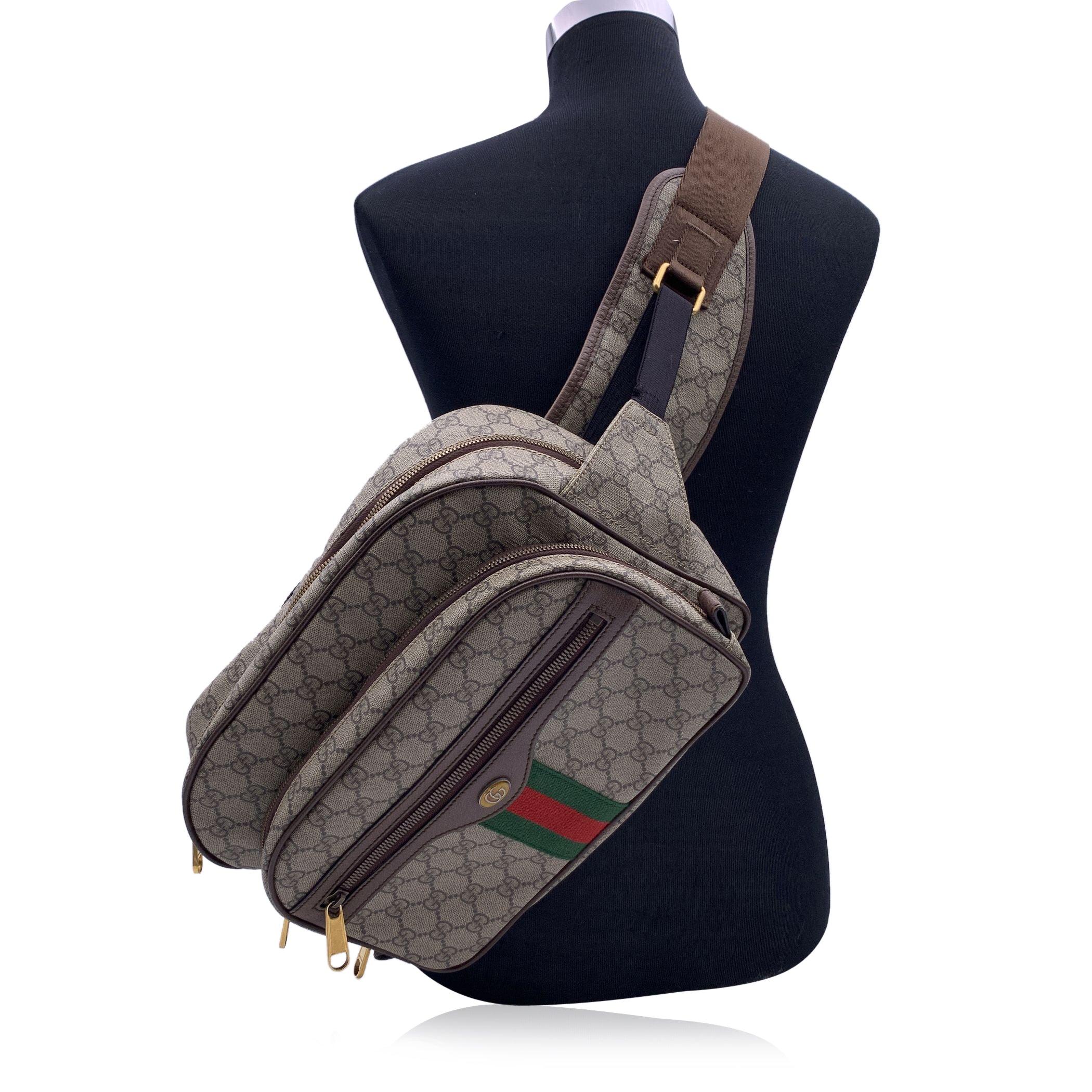 Beautiful large unisex Ophidia waist bag by Gucci. Crafted of GG Supreme canvas with brown leather trims. This model is very versatile; may be worn as belt bag, but also crossbody (as a backpack). Green/red/green stripes on the front and GG enamel