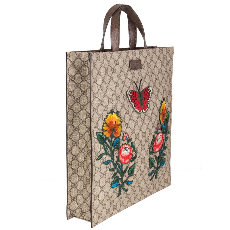 Gucci 'GG Supreme' embroidered tote bag in monogram coated canvas that is printed with Gucci's iconic interlocking G motif.  Multicolor butterlfly and flower embroidery on the front. Brown leather handles and adjustable shoulder strap. Lined in