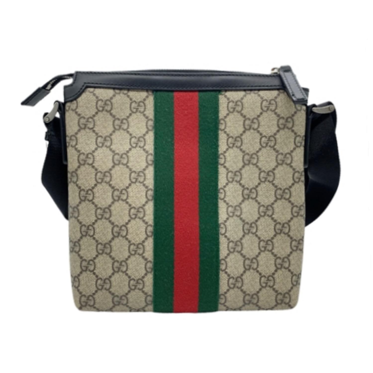 Coated canvas messenger bag in beige featuring logo pattern printed in brown. Buffed black leather trim throughout. Adjustable shoulder strap in black with leather strap pad. Leather logo appliqué at face. Signature striped web trim in green and red