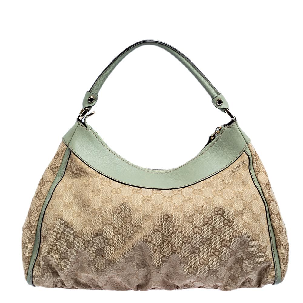 Gucci brings to you this amazing hobo that is smart and modern. Made in Italy, this beige hobo is crafted from GG canvas and green leather trims and features a single handle and a D-shaped ring at the front. The top zip closure reveals a