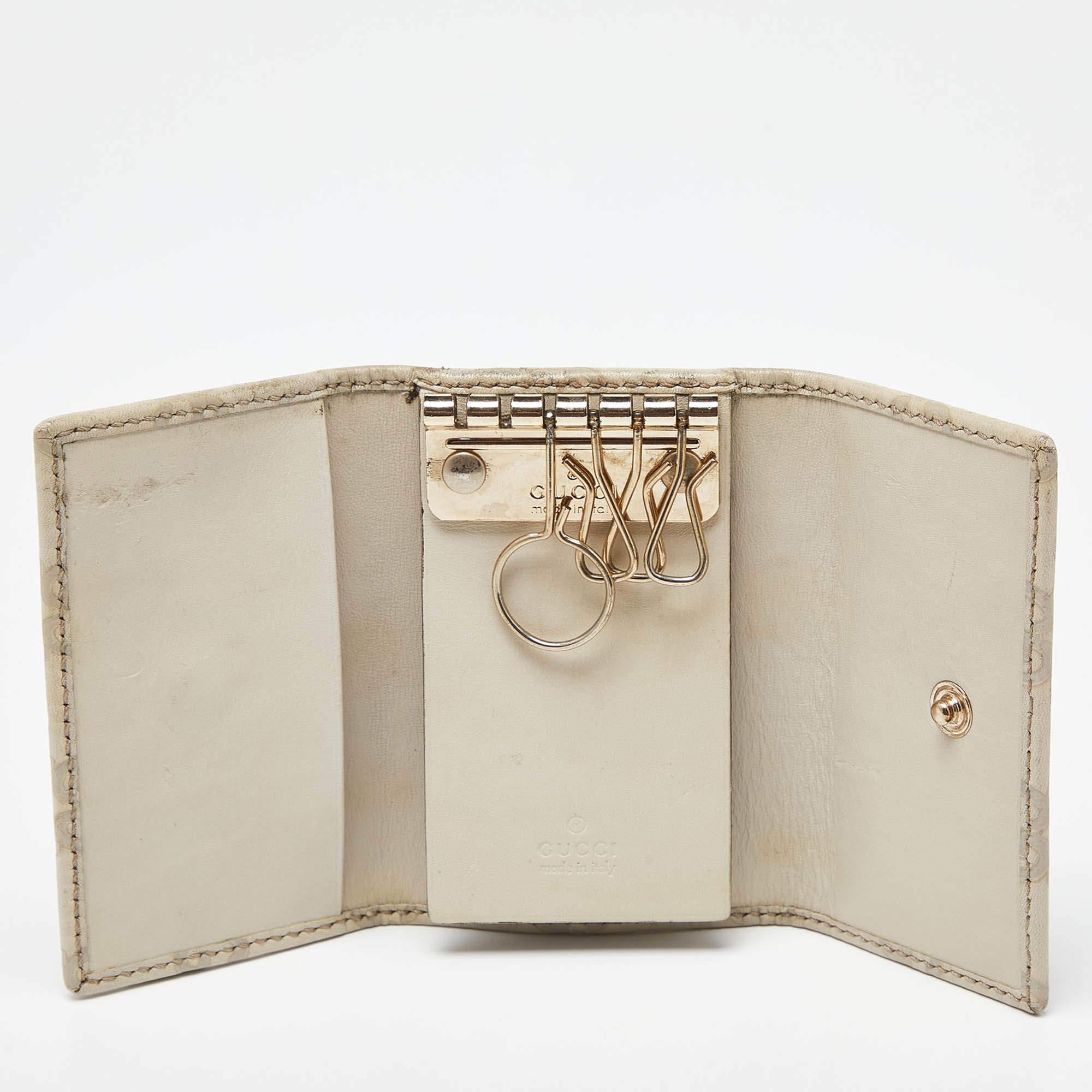 This beige Gucci key holder case is made from Guccissima leather and has fine stitching. The trifold design opens to reveal 6 key holders inside.