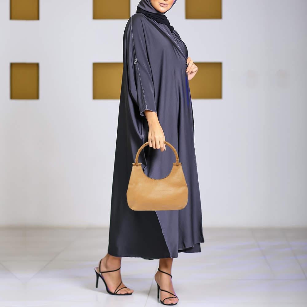 Smoothly glide from day to night with this versatile leather bag that offers a superior design. The well lined suede interior offers ample space and the top bamboo handle comes as the perfect touch. This Gucci accessory ensures comfort and style.