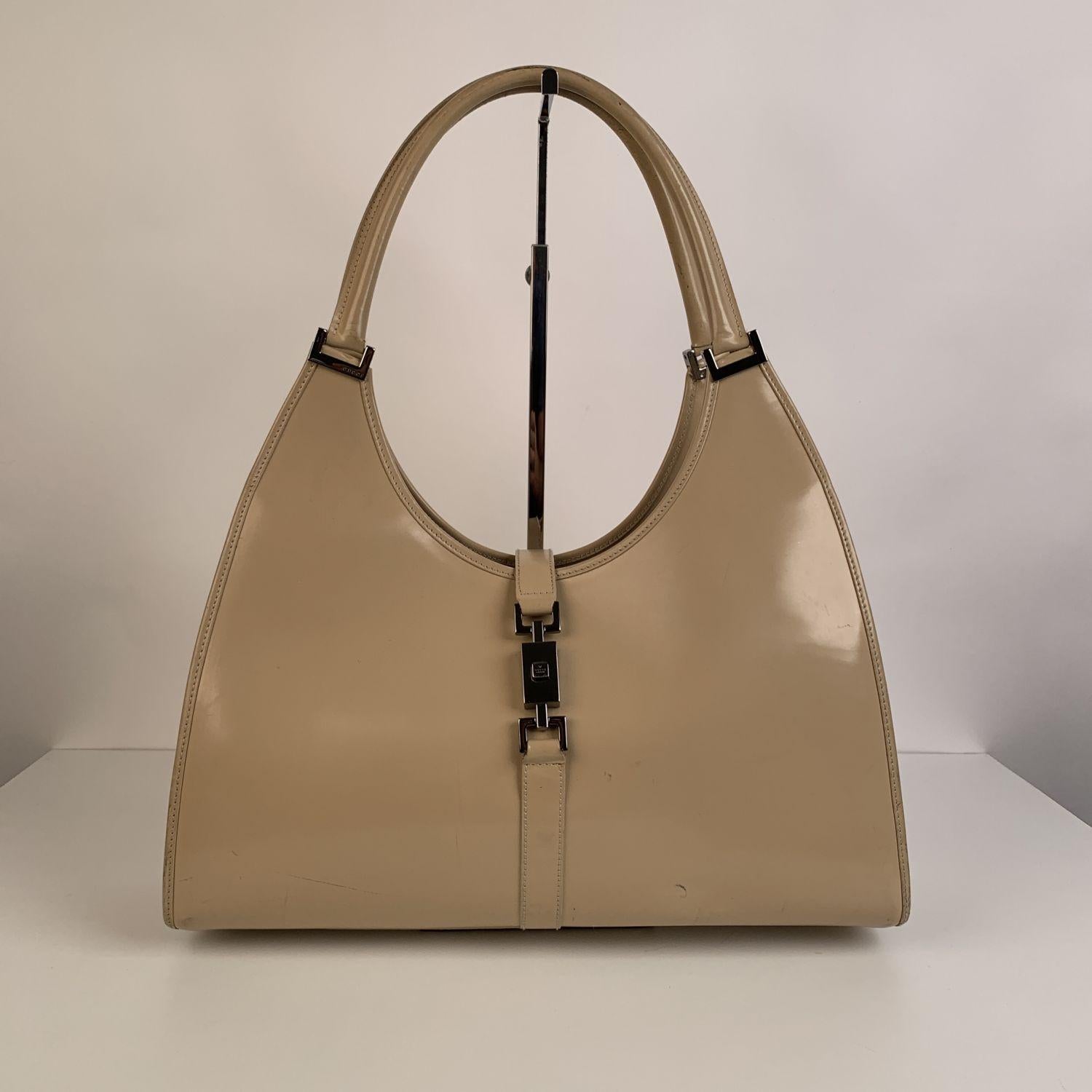 GUCCI Bardot hobo crafted in beige leather. Silver metal hardware. Fold over strap with push closure on the front. Brown monogram fabric lining. 1 side zip pocket inside. 'GUCCI - Made in Italy' tag inside (with serial number on its reverse), 'GUCCI