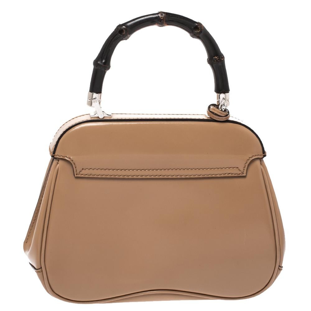 Featuring the iconic Lady Lock, this top handle bag is from Gucci. This bag is crafted from beige leather and features a bamboo top handle. The push-lock closure opens to a suede-lined interior that houses an open compartment. Carry this trendy