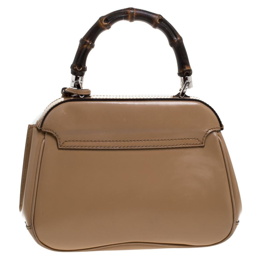 Featuring the iconic Lady Lock, this top handle bag is from Gucci. This bag is crafted from beige leather and features a bamboo top handle. The push lock closure opens to a suede-lined interior that houses an open compartment. Carry this trendy
