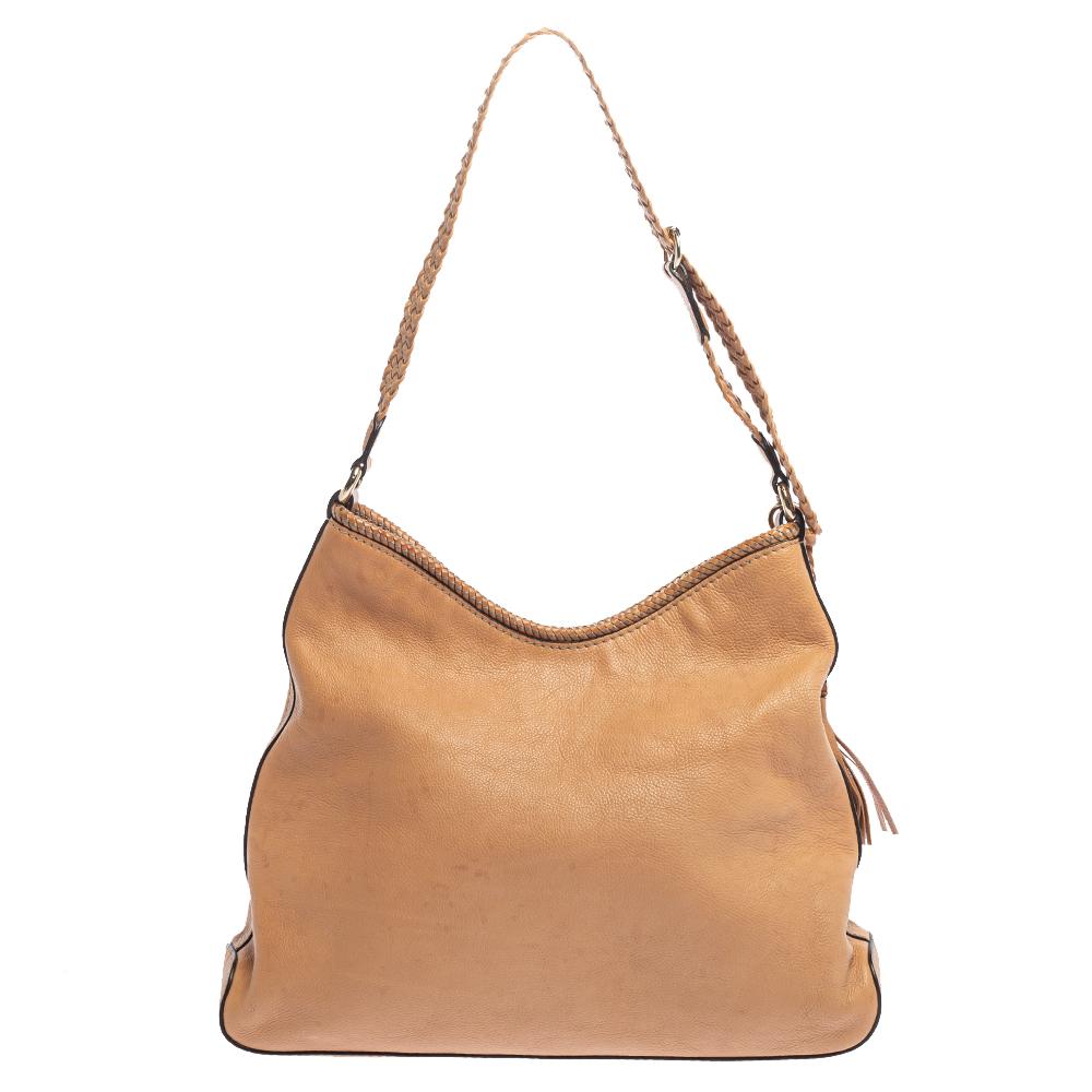 This Gucci Marrakech hobo is crafted from beige leather. It features a snap button fastening and a well-sized canvas interior. The bag is finished with tassel detailing on the side and a braided handle; and overall, it has a beautiful appeal.

