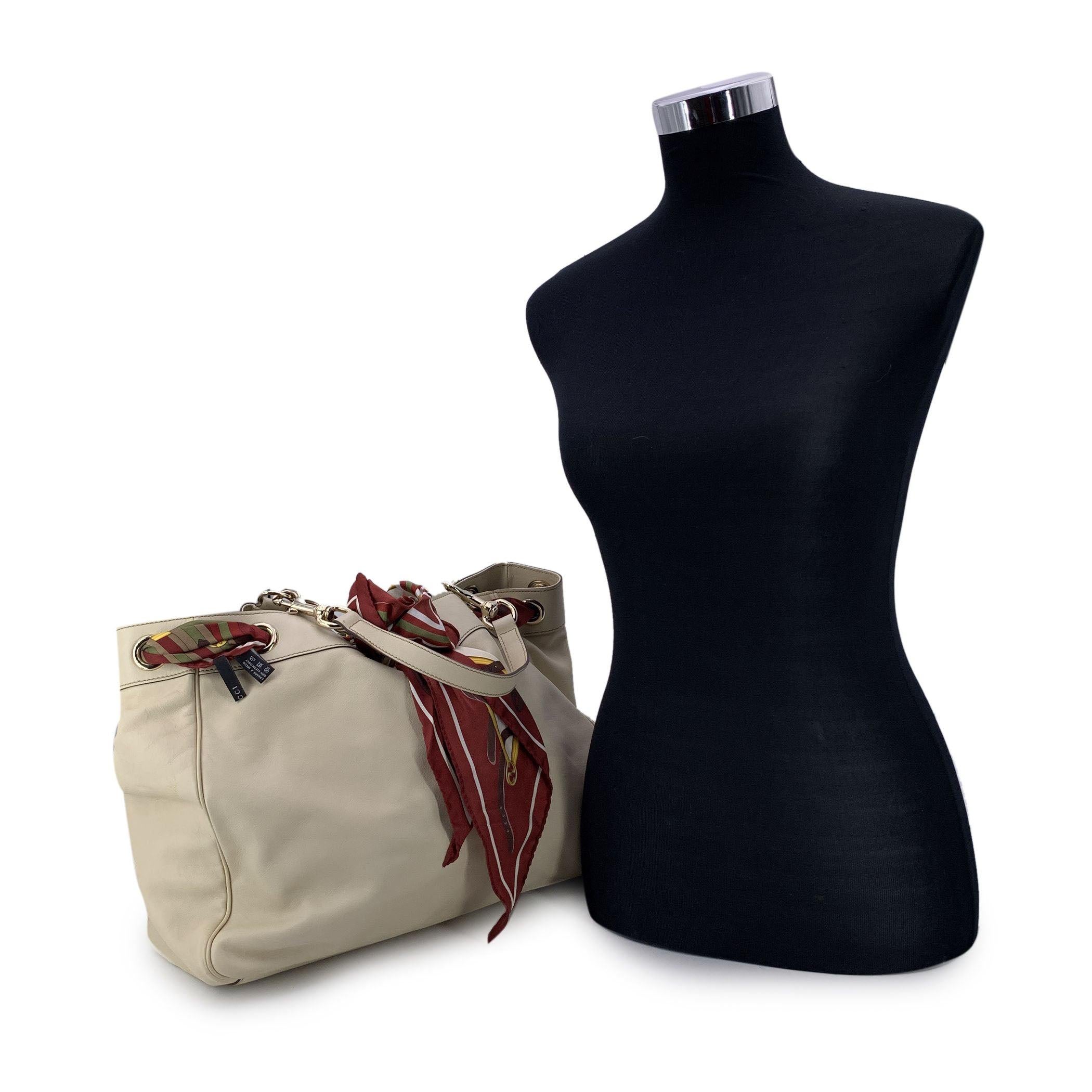 Gucci 'Positano' tote bag crafted in ivory-colored leather. The bag features burgundy silk scarf in burgundy color. Open top. Roomy design. Double removable rounded handles. Brown fabic lining. 1 side zip pocket and 1 side open pocket inside. 'GUCCI