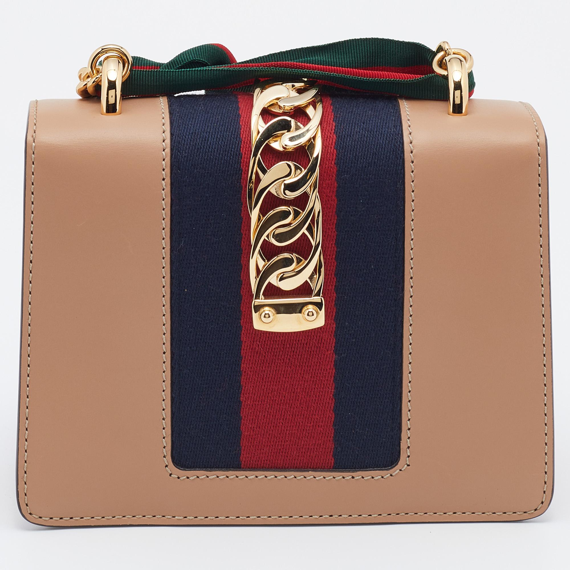 This Sylvie bag from the House of Gucci emerges as an everlasting icon of opulence and elegance with its brilliantly-designed structure. It is crafted from beige leather and it has the iconic Web strap with gold-tone chain detailing on the flap.