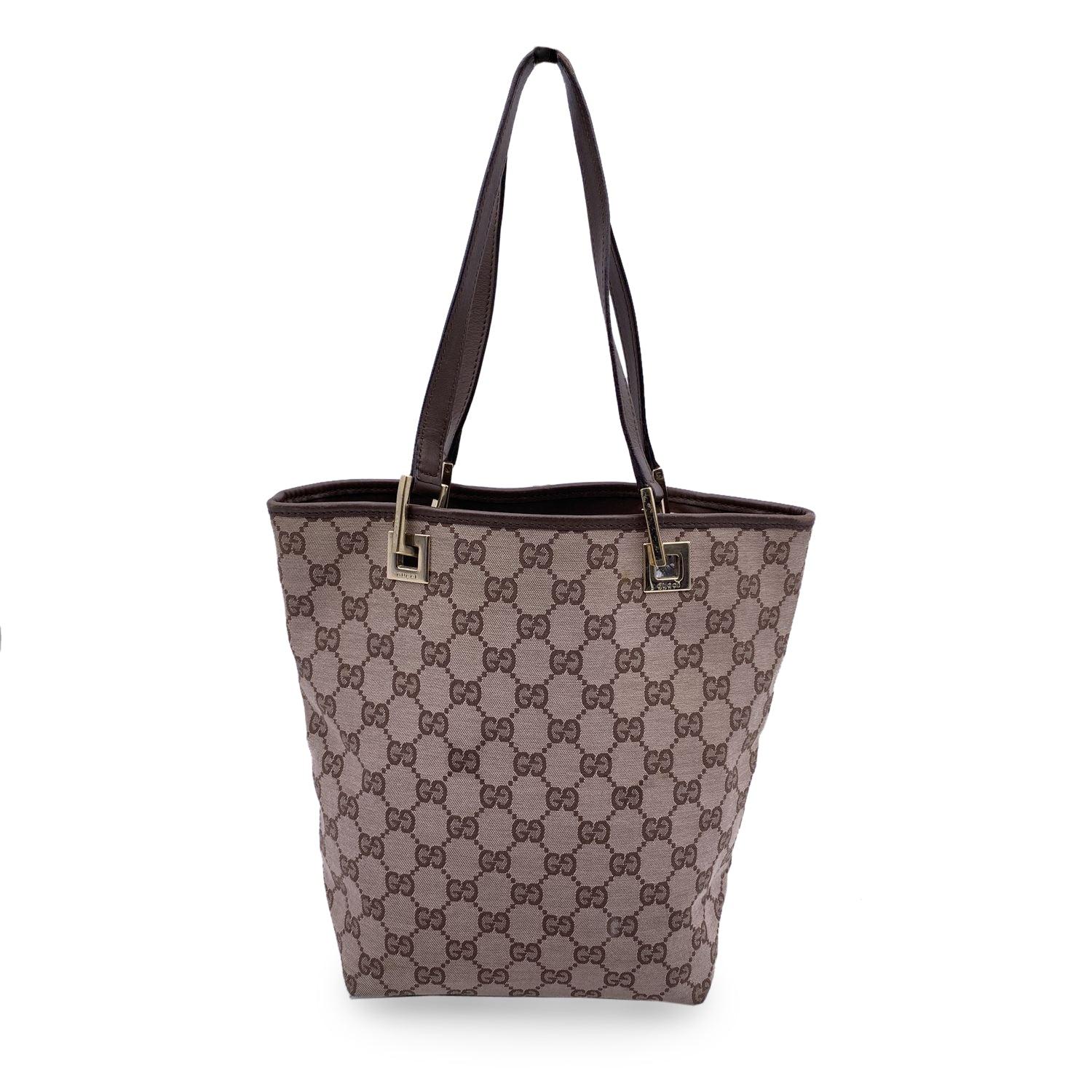 Beautiful Gucci small tote in beige monogram canvas with brown leather trim and handles. Light gold metal hardware. Open top. Brown fabric lining, 1 side zip pocket inside. 'GUCCI - Made in Italy' tag inside (with serial number on its reverse)