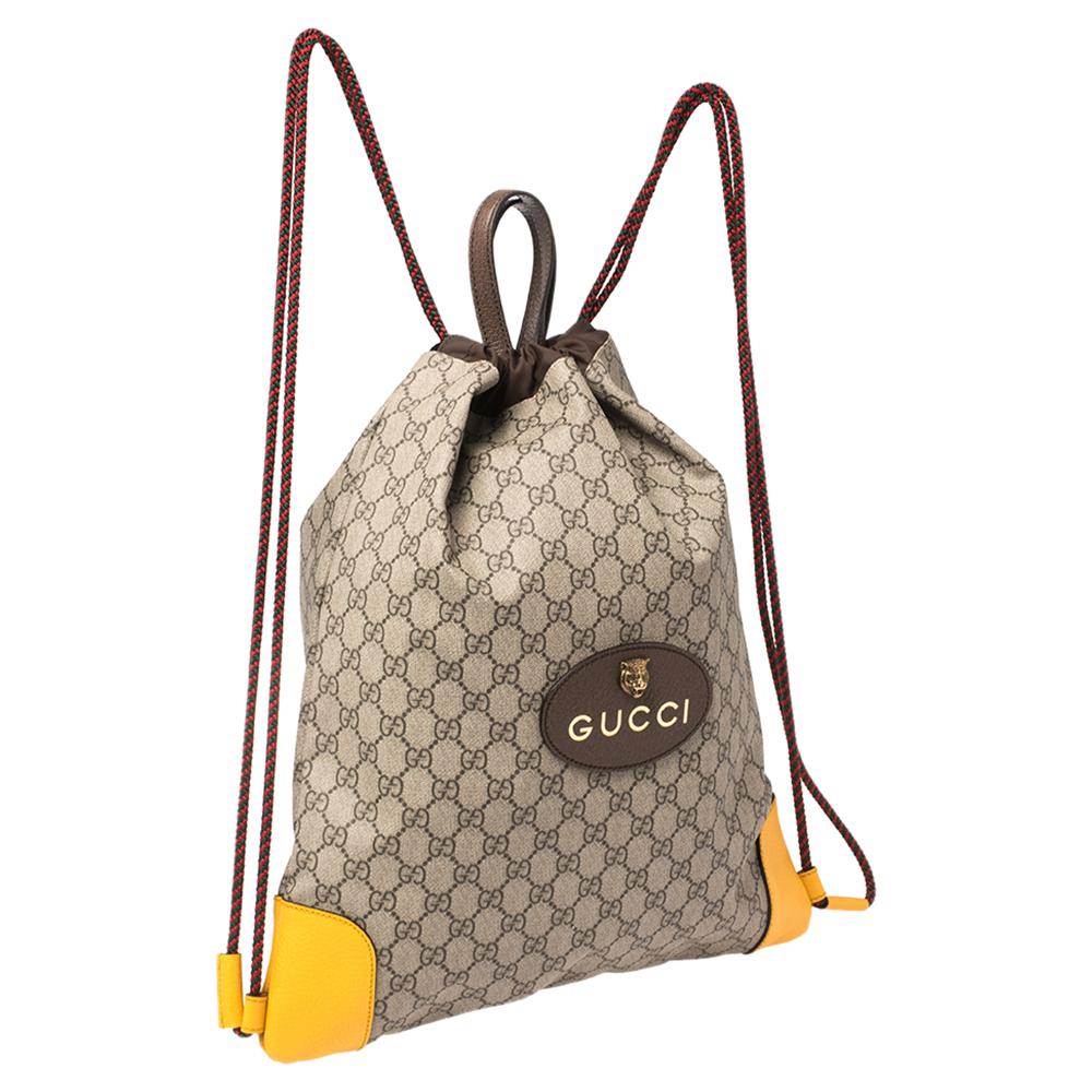 This fabulous backpack is from Gucci. Crafted from GG Supreme canvas and leather, the backpack features the Gucci logo on the front and dual top handles. The drawstring closure opens to a nylon-lined interior that will easily accommodate all your