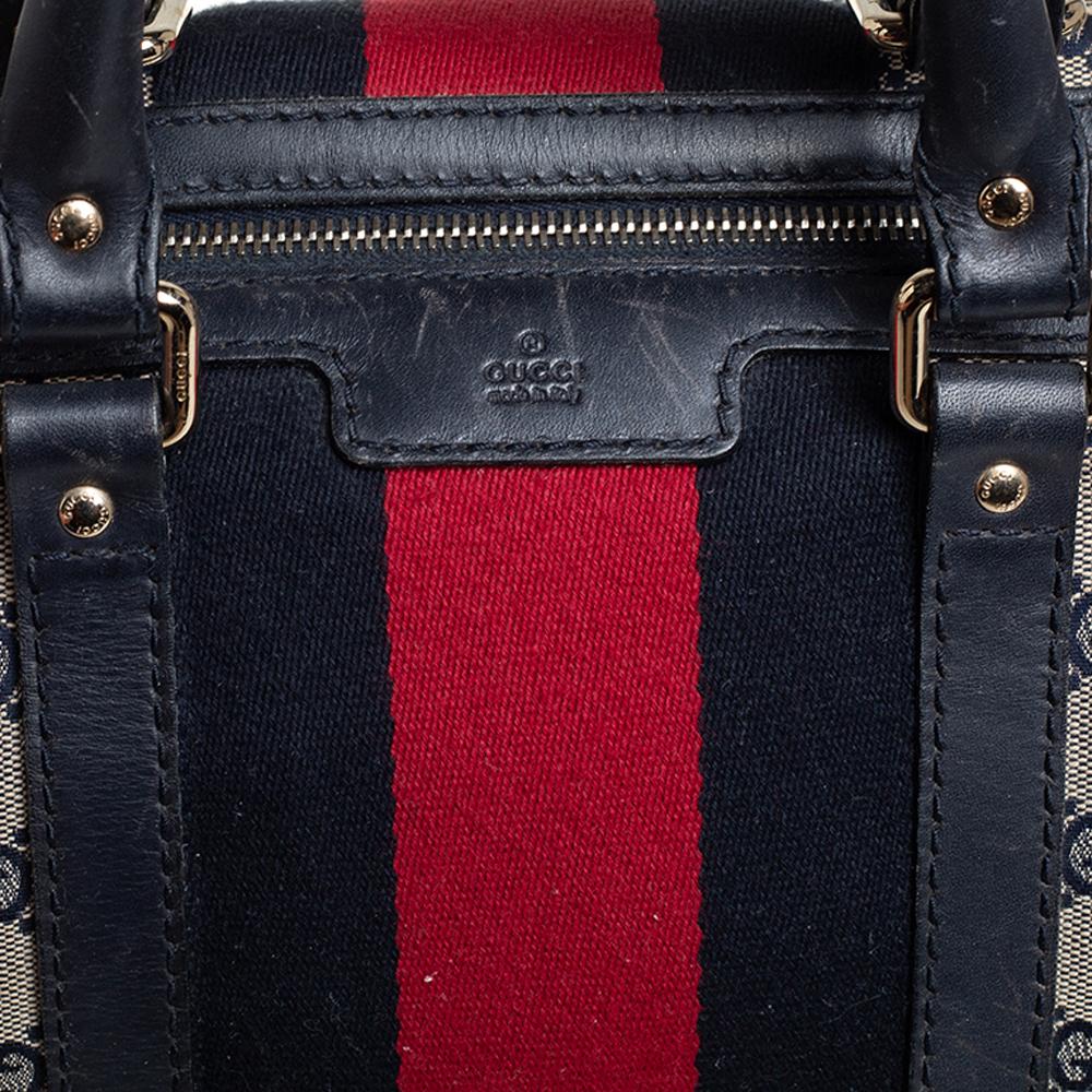 This Gucci Boston bag perfectly blends Gucci’s timeless and iconic style. This bag is made from Gucci’s classic GG canvas in beige, with navy blue leather trims that give it a luxurious touch. It features the signature web detail stripes accented