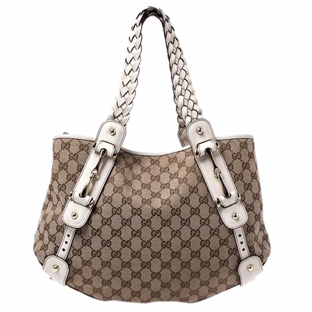 Take your style a notch higher with this Pelham shoulder bag from Gucci. Cut out from the brand's signature GG canvas and leather, it comes in beige and white hues. The bag features two braided leather handles, a spacious fabric interior, and
