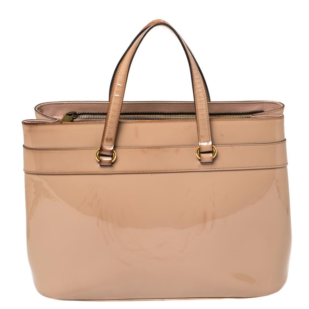 This Bright Bit bag from Gucci proves that style can come in simple things too. Crafted from patent leather, this lovely beige bag features a canvas-lined interior, dual top handles, and an adjustable shoulder strap. It is equipped with gold-tone