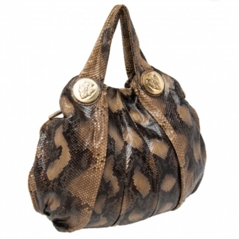 Questa hobo di Gucci è pensata per l'uso quotidiano. Realizzata in pitone, ha un esterno beige e due manici per poterla sfilare facilmente. Gli interni in nylon sono ben dimensionati e la hobo è completa degli emblemi della firma.