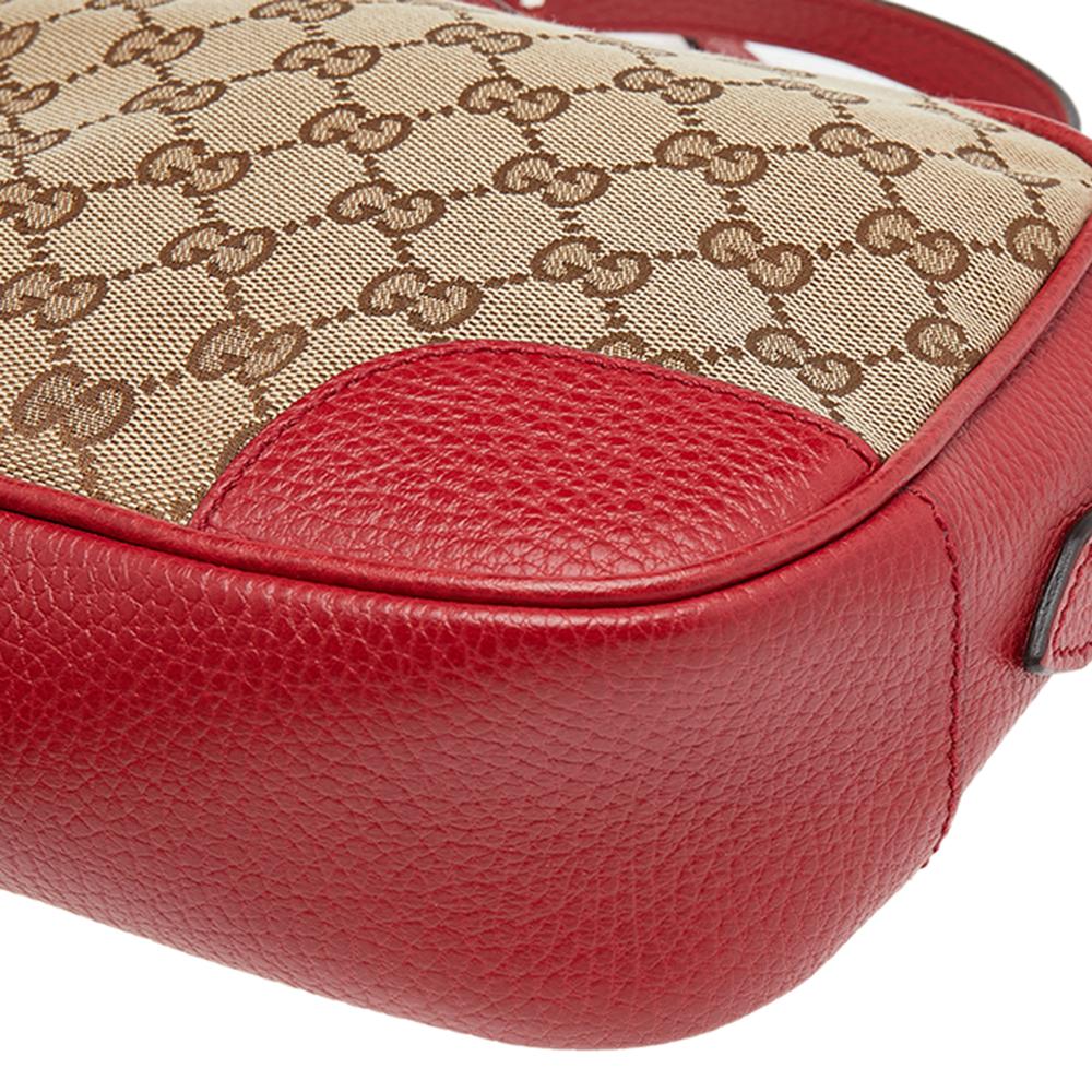 This red and beige bag from Gucci is stylish and functional. Crafted from the signature GG canvas and leather, it features a top zip closure that opens to a canvas-lined interior housing an open compartment, a slip pocket, and multiple card slots.