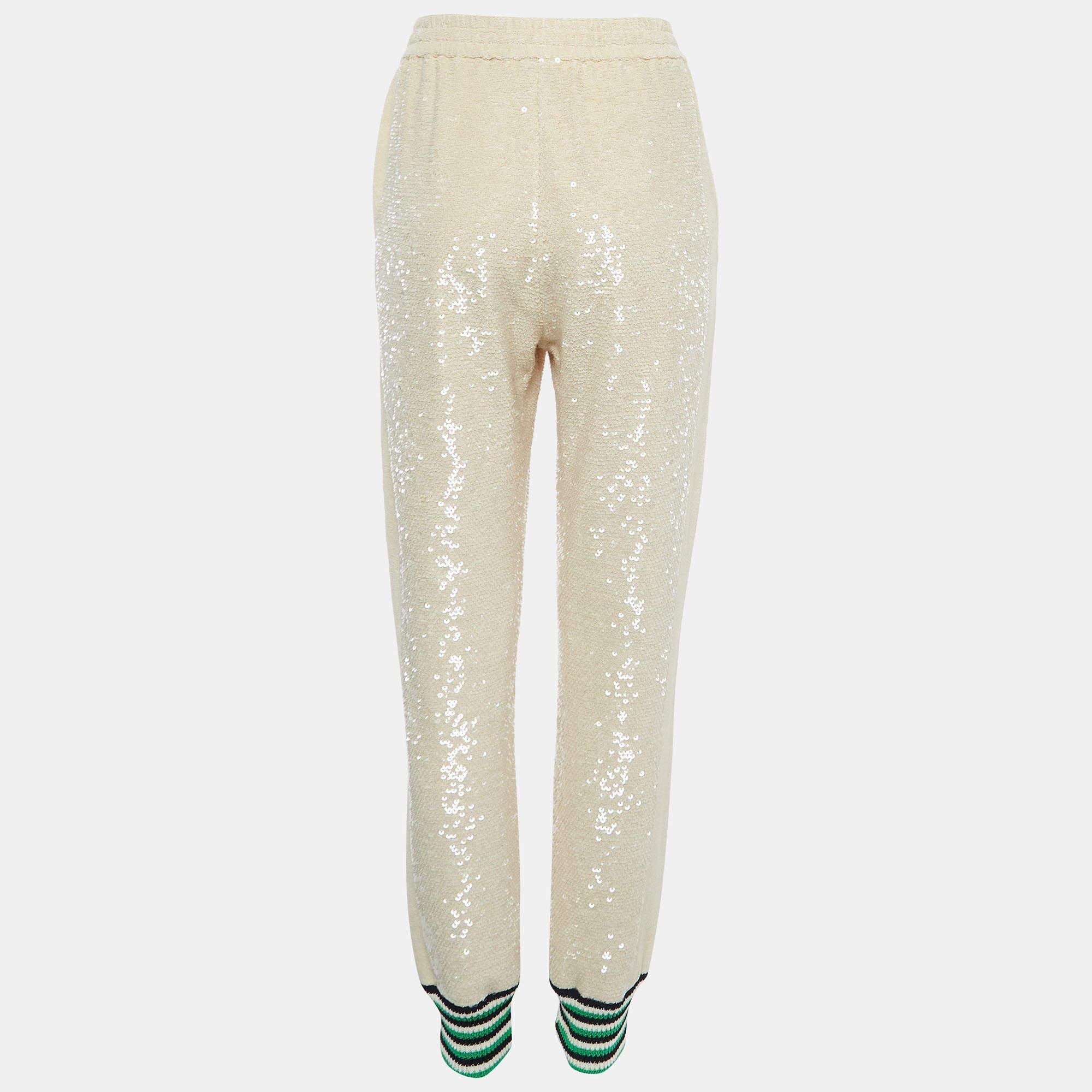 The Gucci joggers feature a luxurious blend of comfort and style. Crafted from high-quality cotton, the joggers showcase a beige hue adorned with sequins, creating a glamorous and effortlessly chic look. The drawstring waist adds a touch of