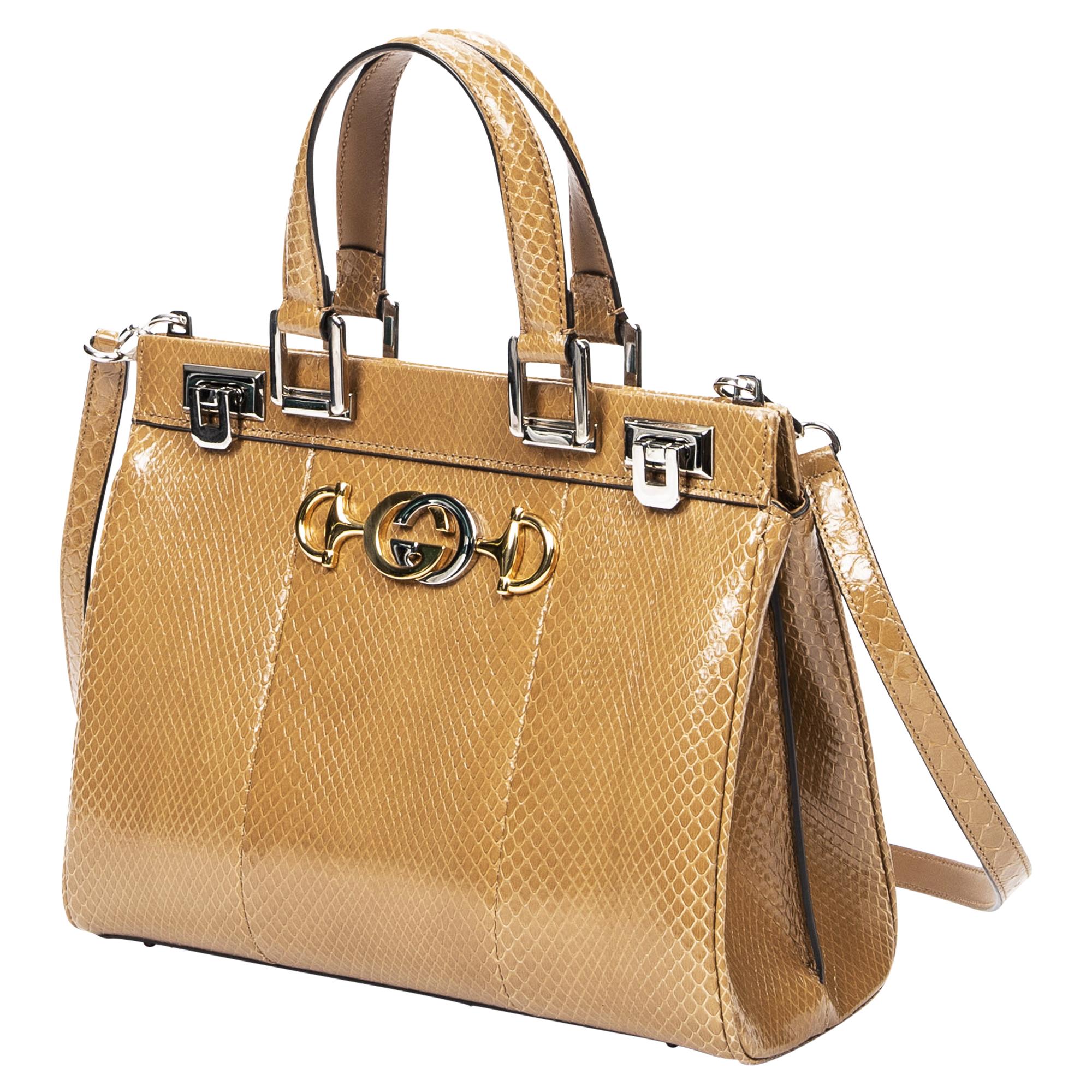 Die Gucci Beige Snakeskin Small Top Handle Bag steht für exotische Eleganz. Aus luxuriösem braunem Schlangenleder in einem vielseitigen Beigeton gefertigt, ist sie ein Statement für die moderne Fashionista. Die Tasche ist mit silbernen Beschlägen