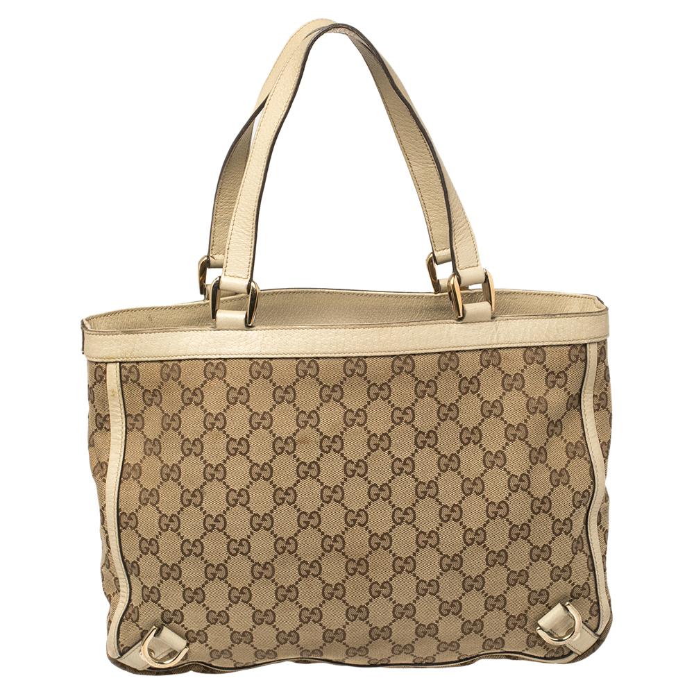 Gucci brings to you this amazing Abbey tote that is a classic. Made in Italy, this beige tote is crafted from the signature GG canvas and white leather and features dual top handles. It flaunts gold-tone D-ring details on the front and back and
