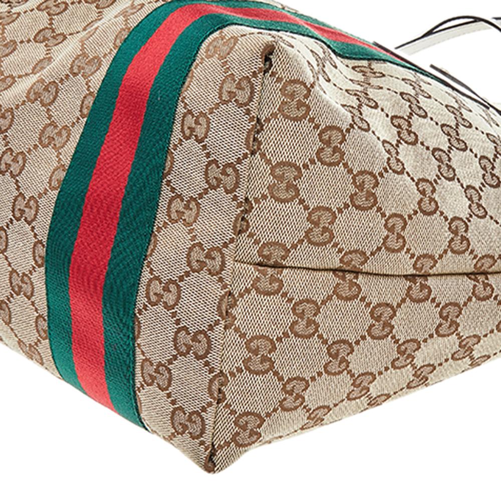 Crafted from monogram GG canvas & patent leather, this tote by Gucci is of perfect size. Its beige & yellow exterior is coupled with the signature Web stripe, double handles, and Gucci charms. Lined with canvas, the open interior includes one zipped