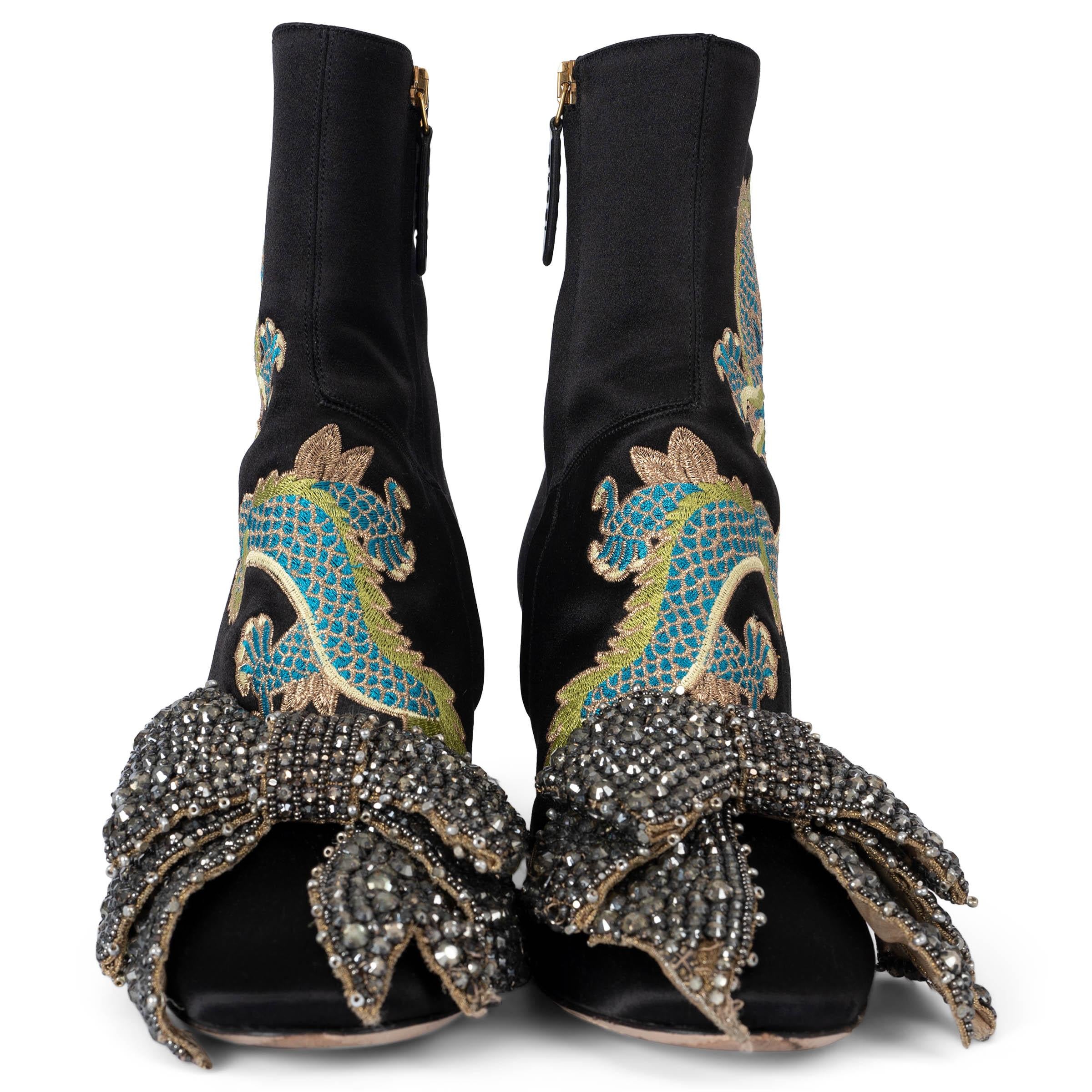 These 100% authentic Gucci Satin Ankle Boots are crafted from luxurious black satin, featuring intricate lime green, petrol and golden lurex dragon embroidery for a unique and chic design. The boots are adorned with a crystal-covered heel, adding a
