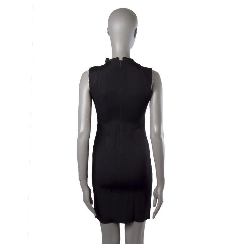 Gucci sheath dress in black acetate (78%) and viscose (32%). With piped crew neck that ties on the side, application on the front of the neck in golden metal, and slit on one shoulder. Closes with one hook and invisible zipper on the back. Lined in