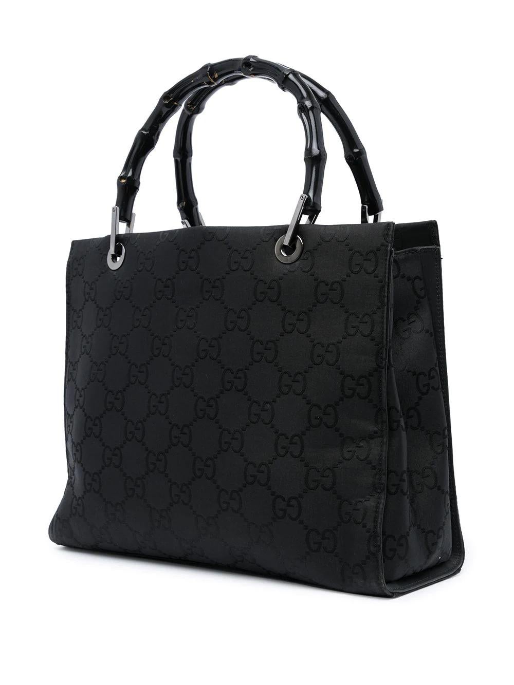 This vintage Gucci Black Canvas Bag features the signature GG logo print, bamboo handles, an open top and interior zip compartments, adding style and chic to any outfit.

Colour: Black

Composition: Body: Fabric 100%, Top: Bamboo 100%, Trims: