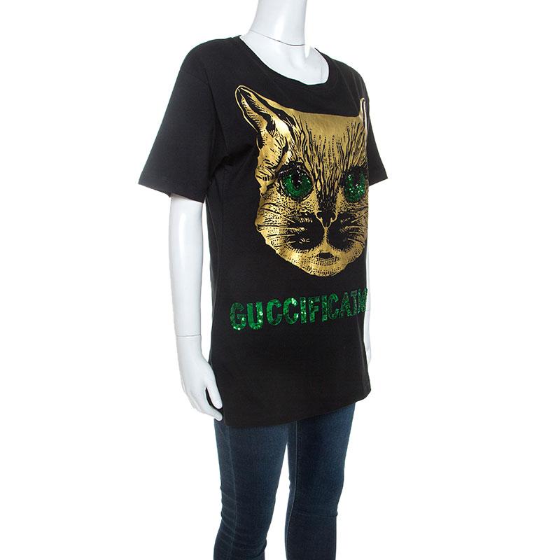 This Gucci top will make for a lovely addition to your wardrobe. Crafted from 100% cotton, it comes in a classic black color. The front is made interesting with the iconic black cat print in gold with the eyes and the word 'Guccification' adorned in