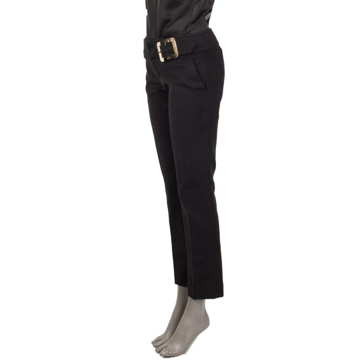 authentic Gucci tapered pants in black cotton (97%) and elastane (3%) with a silver-tone metal buckle detail at the waist-line. Closes with two hooks and a zipper on the front and has slit pockets. Unlined. Has been worn and is in excellent