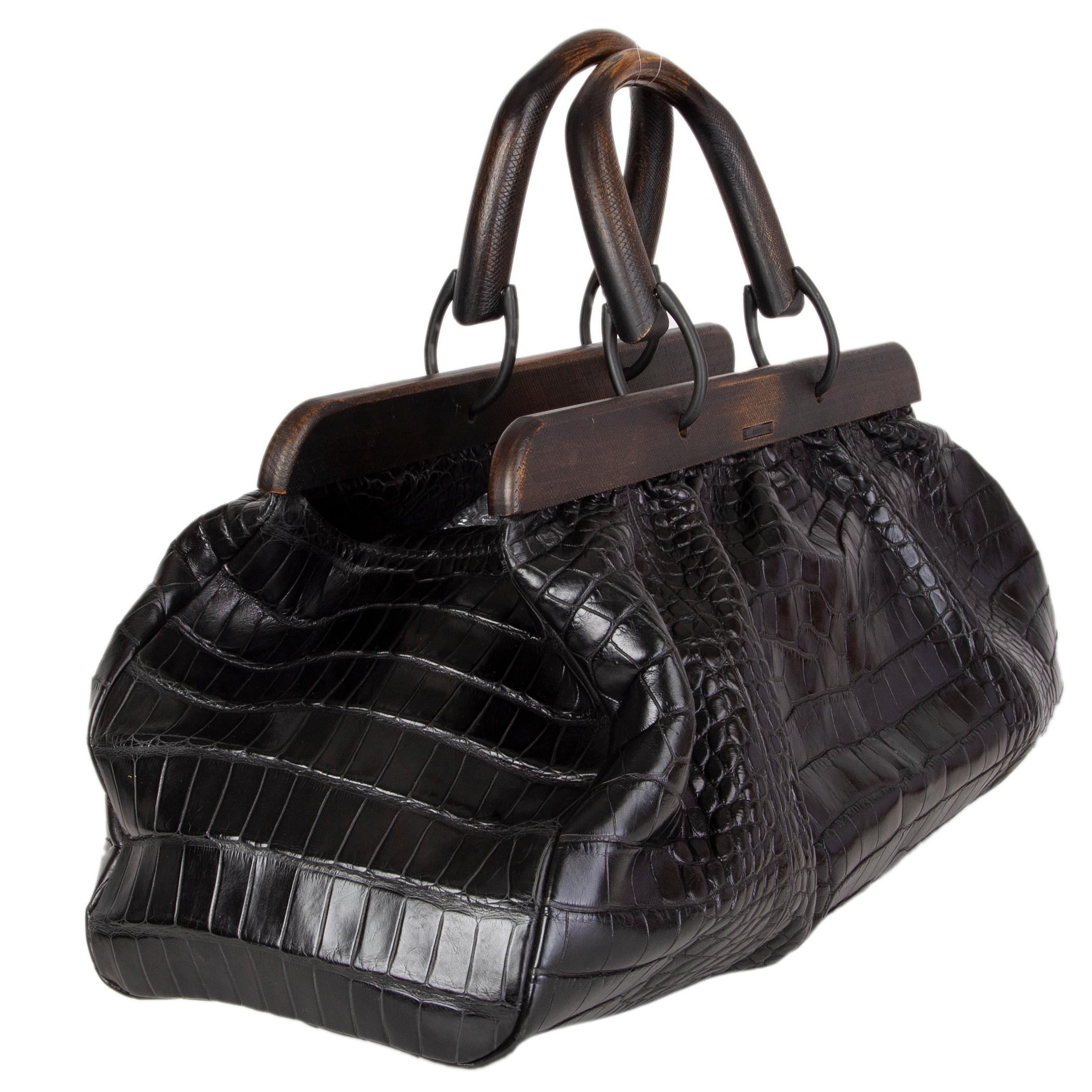 Gucci by Tom Ford docotors bag in black soft crocodile with distressed wooden handles. Vintage 2002. Closes with a belt on top. Lined in black leather with a zipper pocket against the back. Has been carried and is in excellent condition.

Height