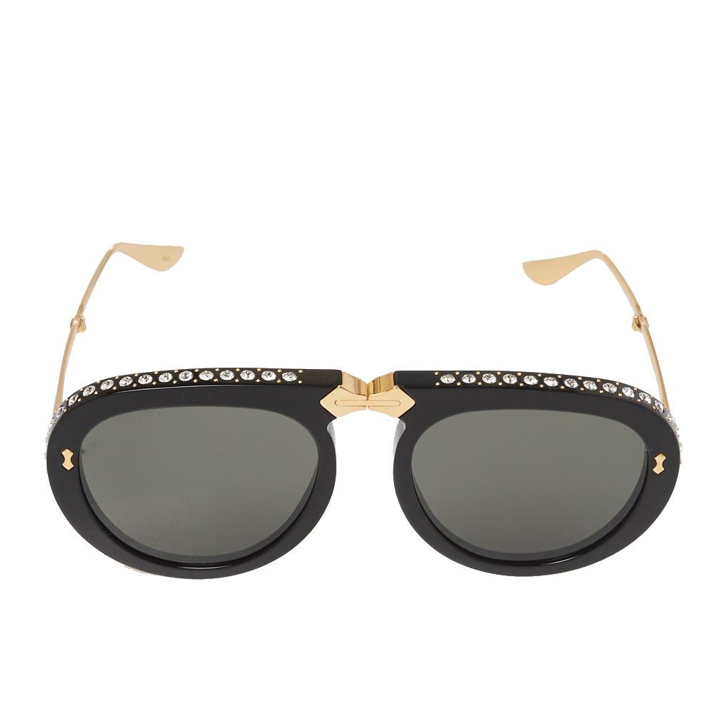These gorgeous Gucci Pilot aviators are made from gold-tone metal and acetate. The fame is accented with crystals embellishments on the contours and the temples are enhanced with the brand name engravings. The grey-hued lenses make the pair