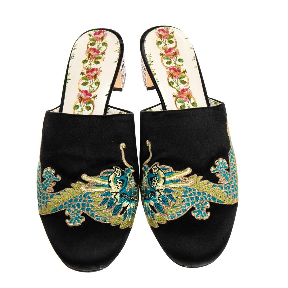 Gucci yet again brings a stunning set of mules that makes us marvel at its beauty and craftsmanship. Crafted from black satin, the exterior is adorned with intricate embroidery that reflects the label's craftsmanship. The mules are set on