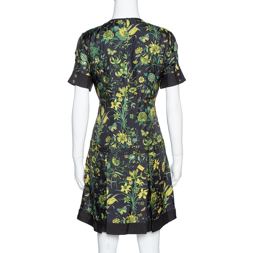 Dress up for an upcoming event in this stunning Gucci dress. This mini dress has been crafted from pure silk and carries a lovely shade of black. The dress is styled with a floral print and bamboo chain detailing in the front that adds interest. The