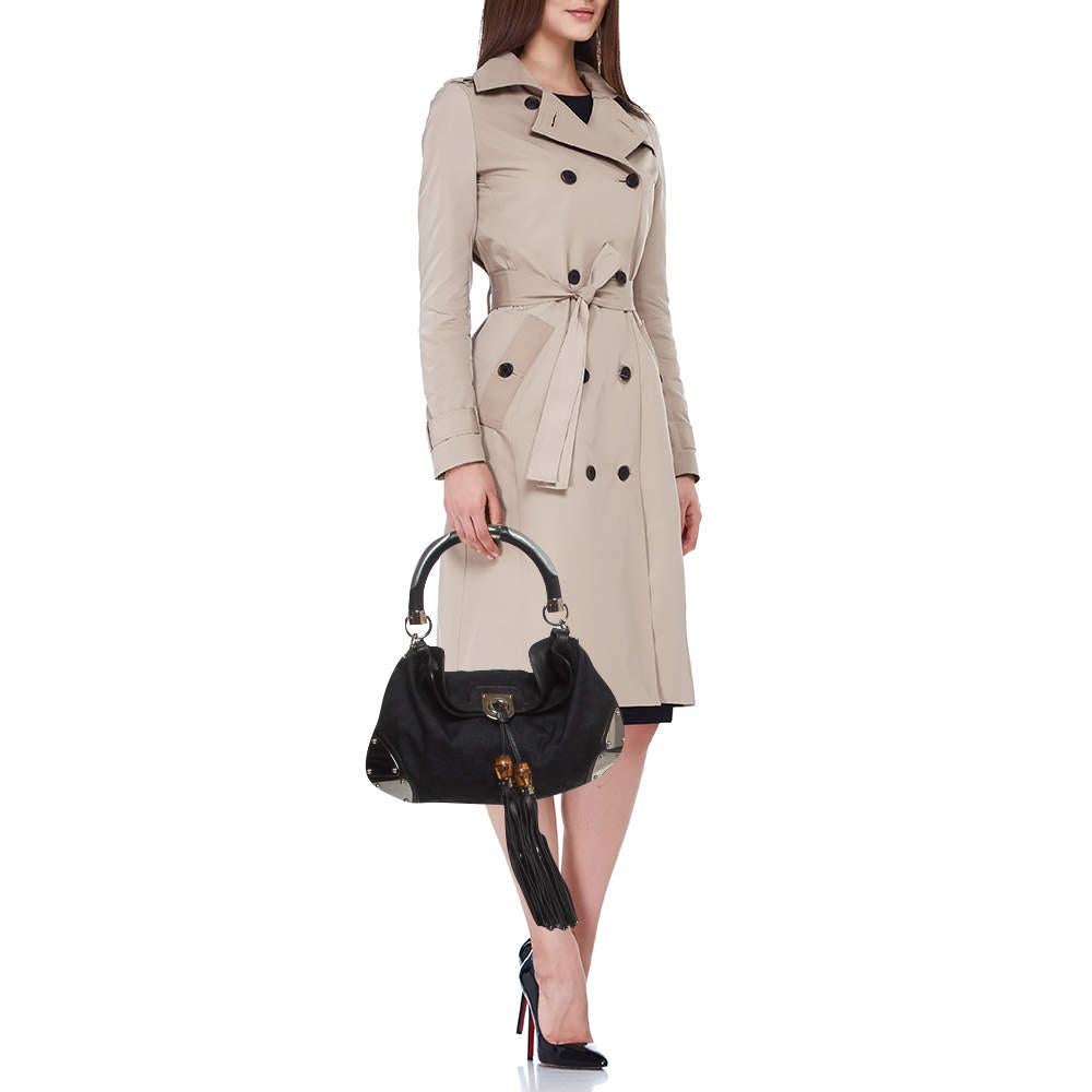 This Babouska Indy hobo is an iconic and beloved creation from the House of Gucci. It is crafted using black GG canvas and leather, with two tassels motifs hanging from the front. It flaunts decorative armored corners and silver-tone hardware. Lined