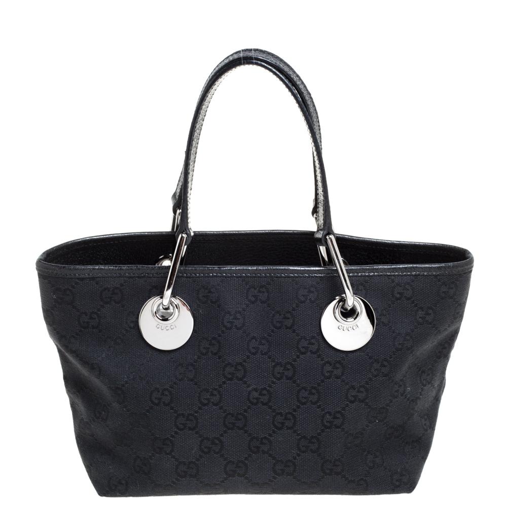 Diese Mini Eclipse Tote von Gucci ist eine äußerst attraktive und stilvolle Kreation. Sie wurde in Italien aus GG-Canvas und Leder gefertigt und so geformt:: dass sie Klasse und Luxus ausstrahlt. Die schwarze Tasche verfügt über zwei Henkel:: ein