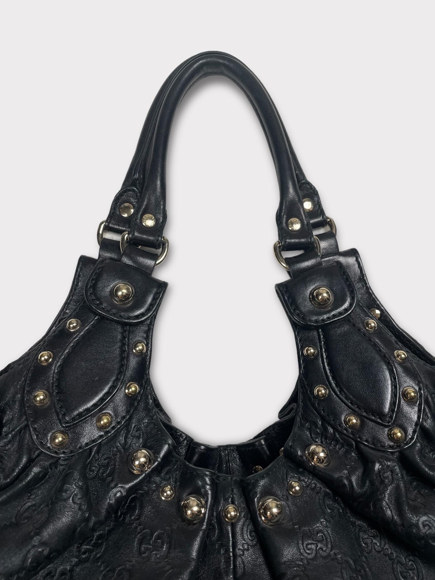 Gucci Studded Pelham Black Tote features a chic design with gorgeous pleated and studded details on gorgeous and supple Gucci monogram embossed leather. 
The bag features studs on the top trim with rolled leather top handles. This opens to a fabric