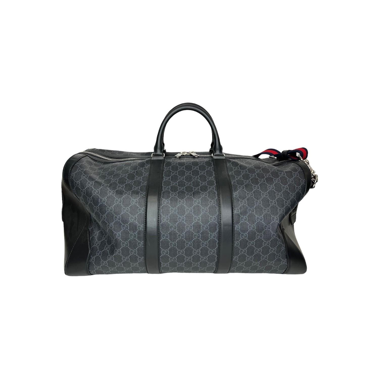 This Gucci duffle bag was made in Italy and it is finely crafted of Gucci's popular black GG Supreme coated canvas with black leather trimmings and silver-tone hardware features. It has rolled black leather top handles and it comes with a removeable