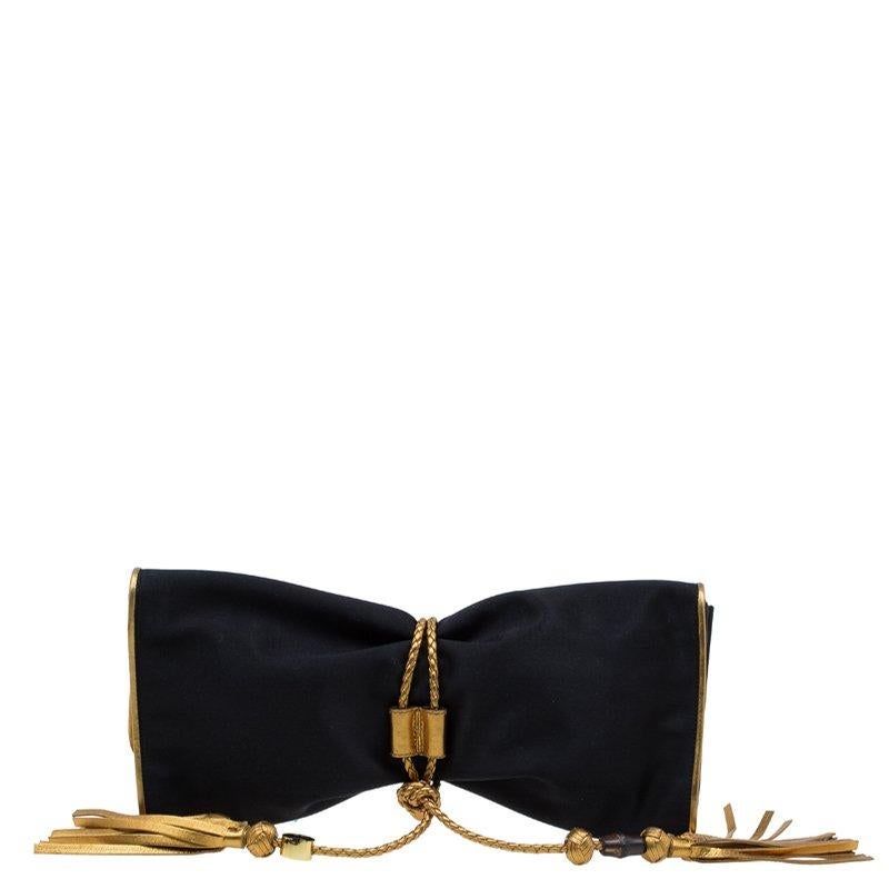 Adorn your evening outfit by carrying this gorgeous and captivating Malika Clutch from Gucci. Crafted from satin, it features an attractive gold borderline. It is accentuated with a fold-over flap, a braided knot and tasseled wraparound strap to
