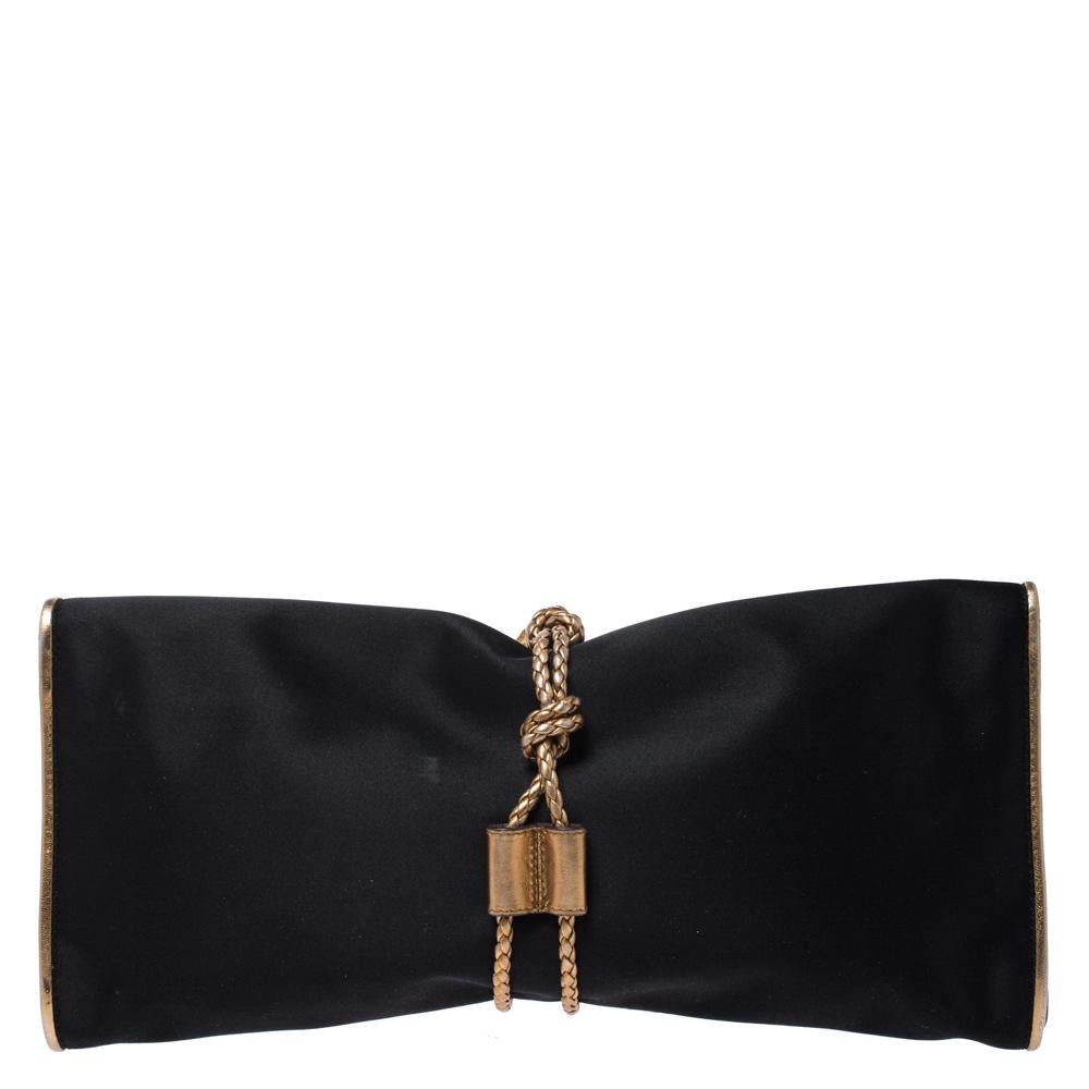 Adorn your evening outfit by carrying this gorgeous and captivating Malika Clutch from Gucci. Crafted from satin, it features an attractive gold leather borderline. It is accentuated with a fold-over flap, a braided knot and tasseled wraparound