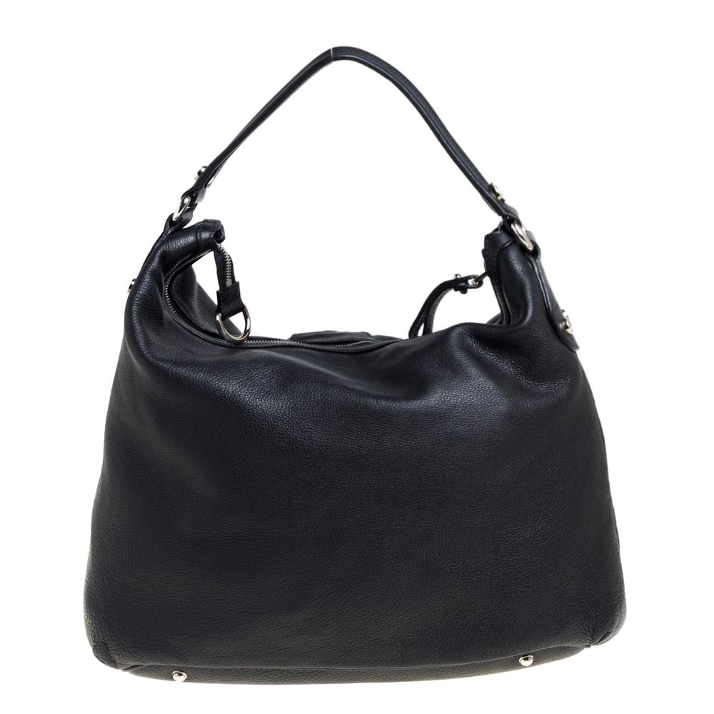 This Gucci creation is stylish, sophisticated & versatile. Crafted meticulously from grained leather, it carries a classy black shade. It is styled with a single handle that is anchored by silver-tone rings. The hobo flaunts a front flap pocket that