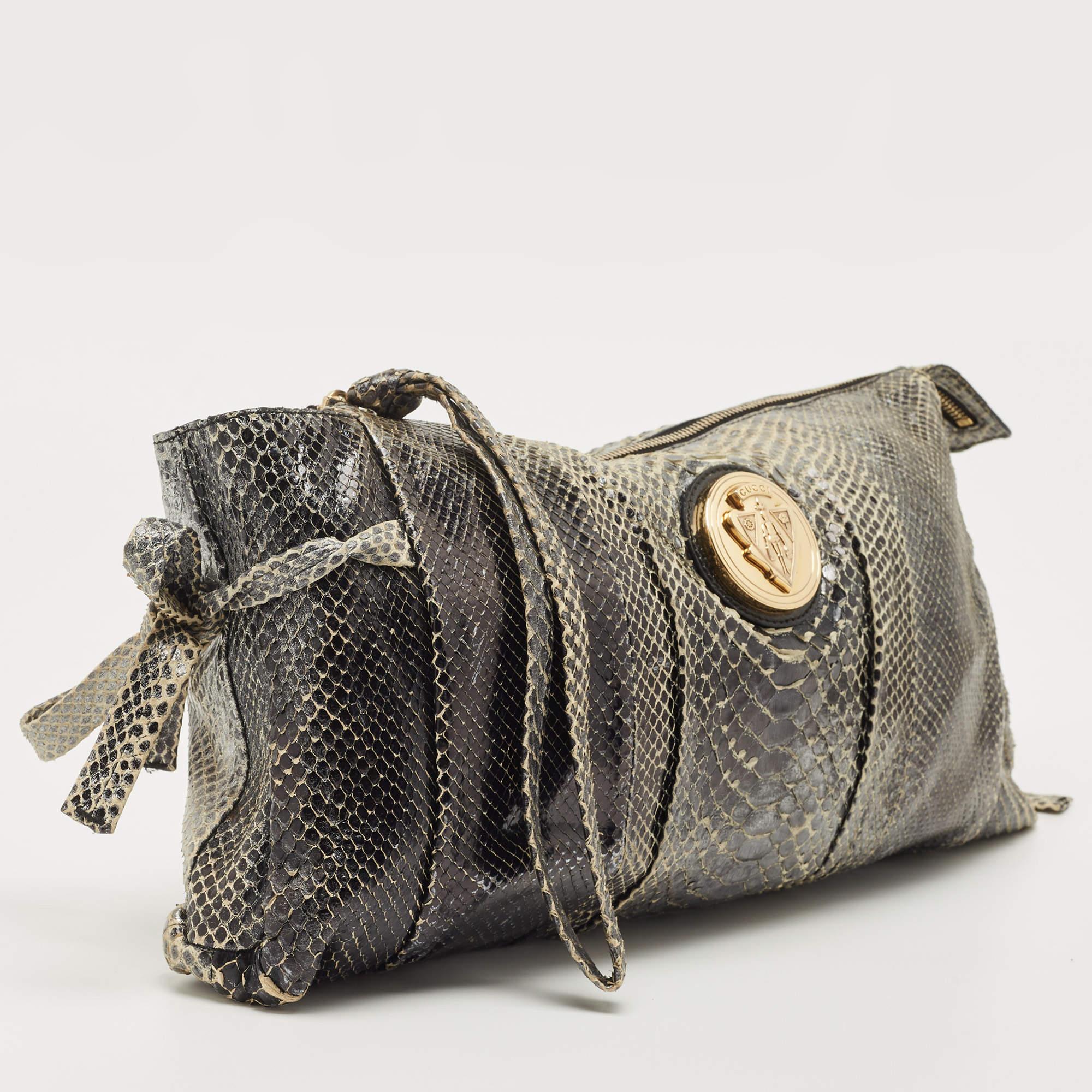 This Gucci clutch is built to suit your stylish ensembles. Crafted from python skin, it has ties on the sides and a zipper which secures a nylon interior. It is complete with the signature Hysteria emblem on the front and a wristlet.

