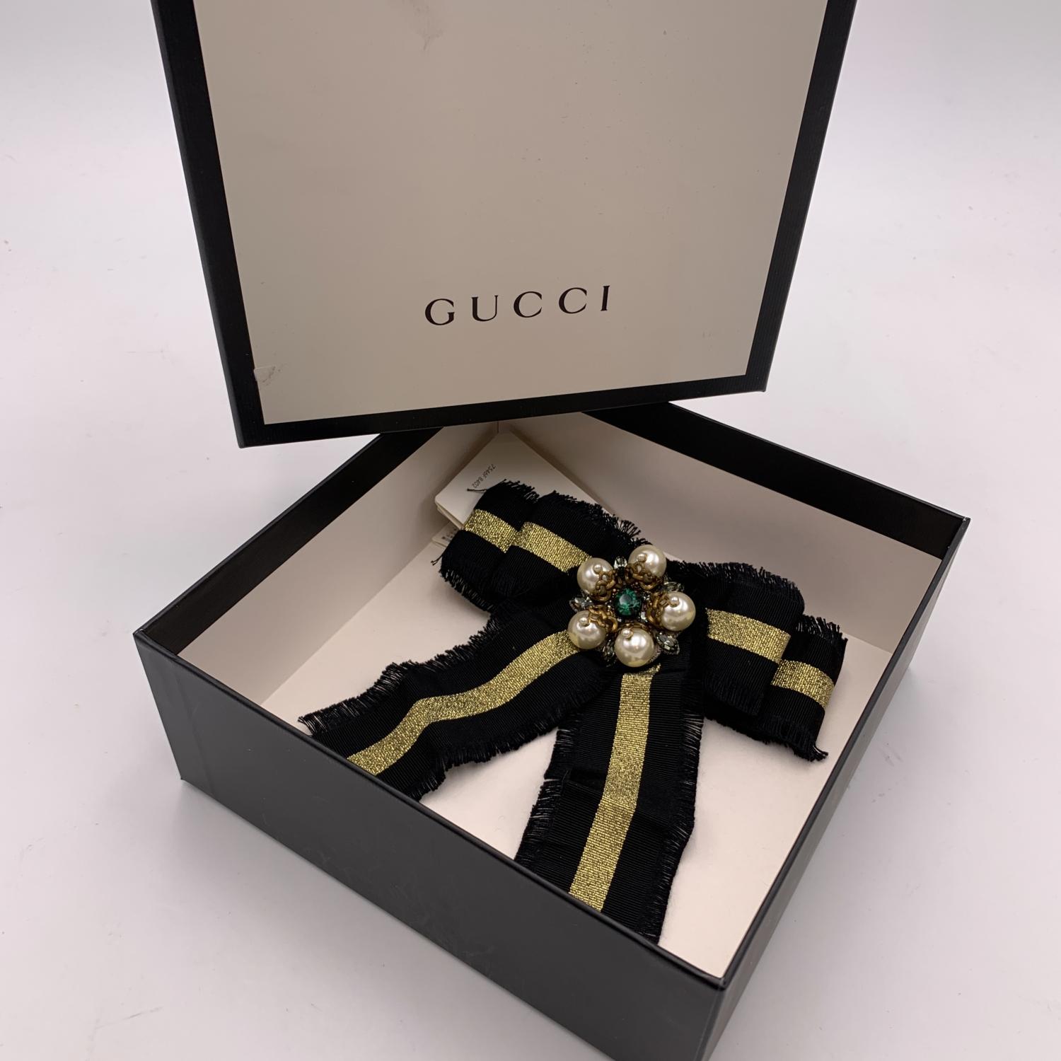 Beautiful Gucci black and gold striped grosgrain bow brooch. Pearls and rhinestones embellishment on the front. Frayed edges. Safety pin closure on the back. Approx. width: 6 inches - 15.2 cm. Approx. height: 6.5 inches - 16.5 cm. Signed 'Gucci' on