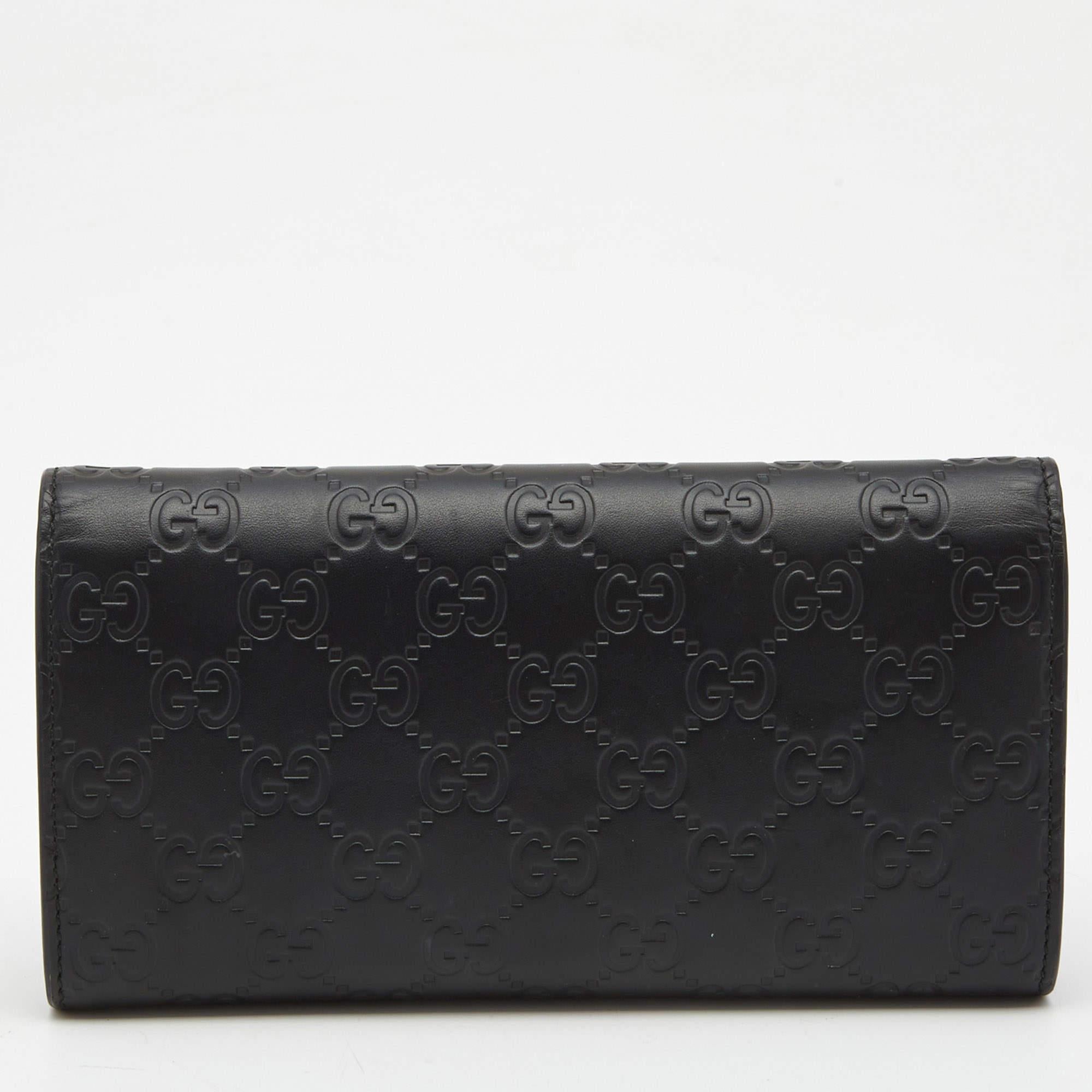 This stylish and practical wallet from the house of Gucci is designed in a gorgeous shade of black from the brand's signature Guccissima leather. Featuring a flap silhouette, this wallet is secured with a snap-button closure and comes with the