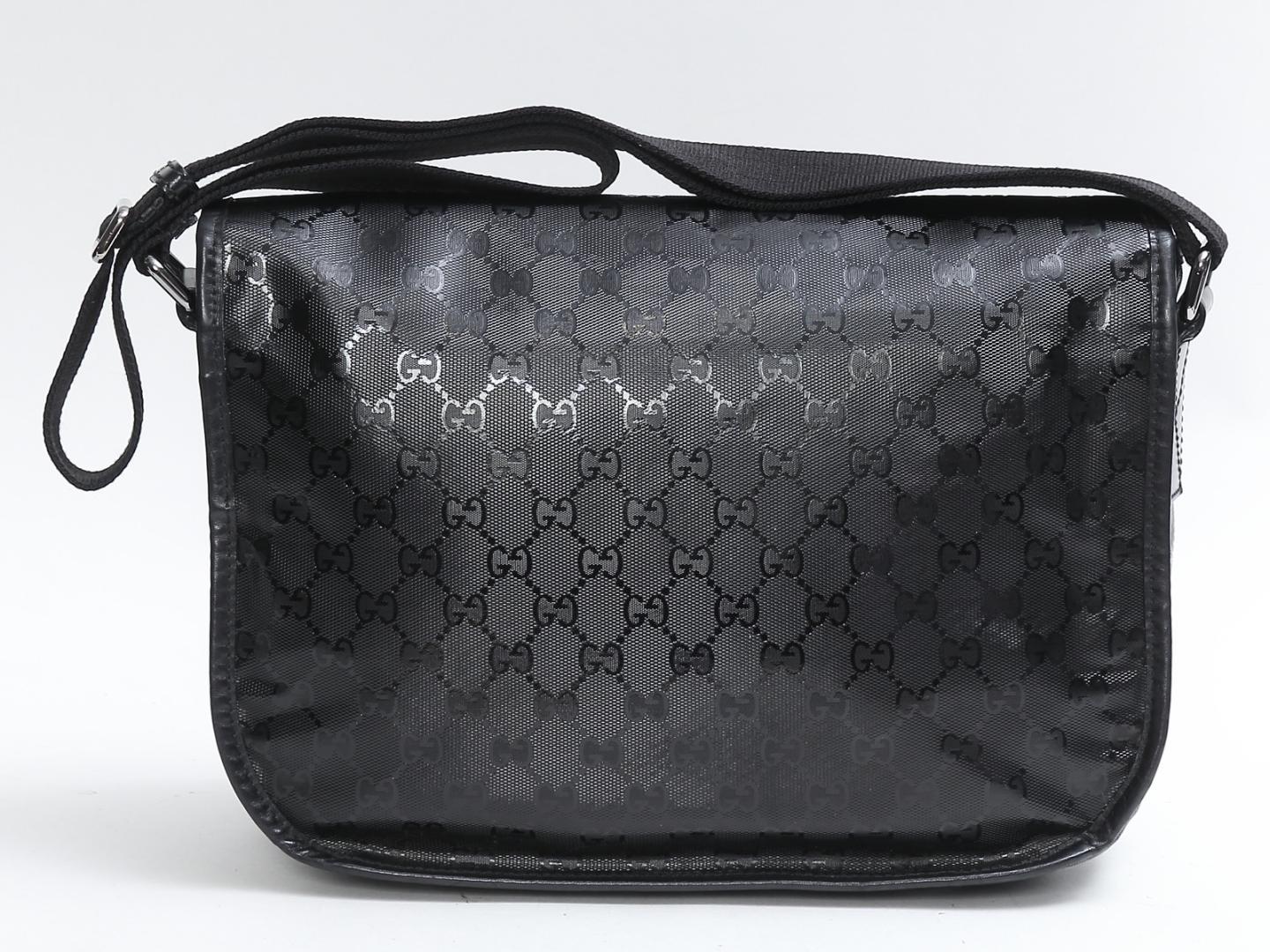 Esta bolsa de mensajero Gucci está confeccionada con tejido Gucci monogram imprime. El bolso tiene ribetes de piel negra, una correa cruzada ajustable de nailon negro y herrajes de plata oscura pulida. El cierre de hebilla de la solapa delantera se