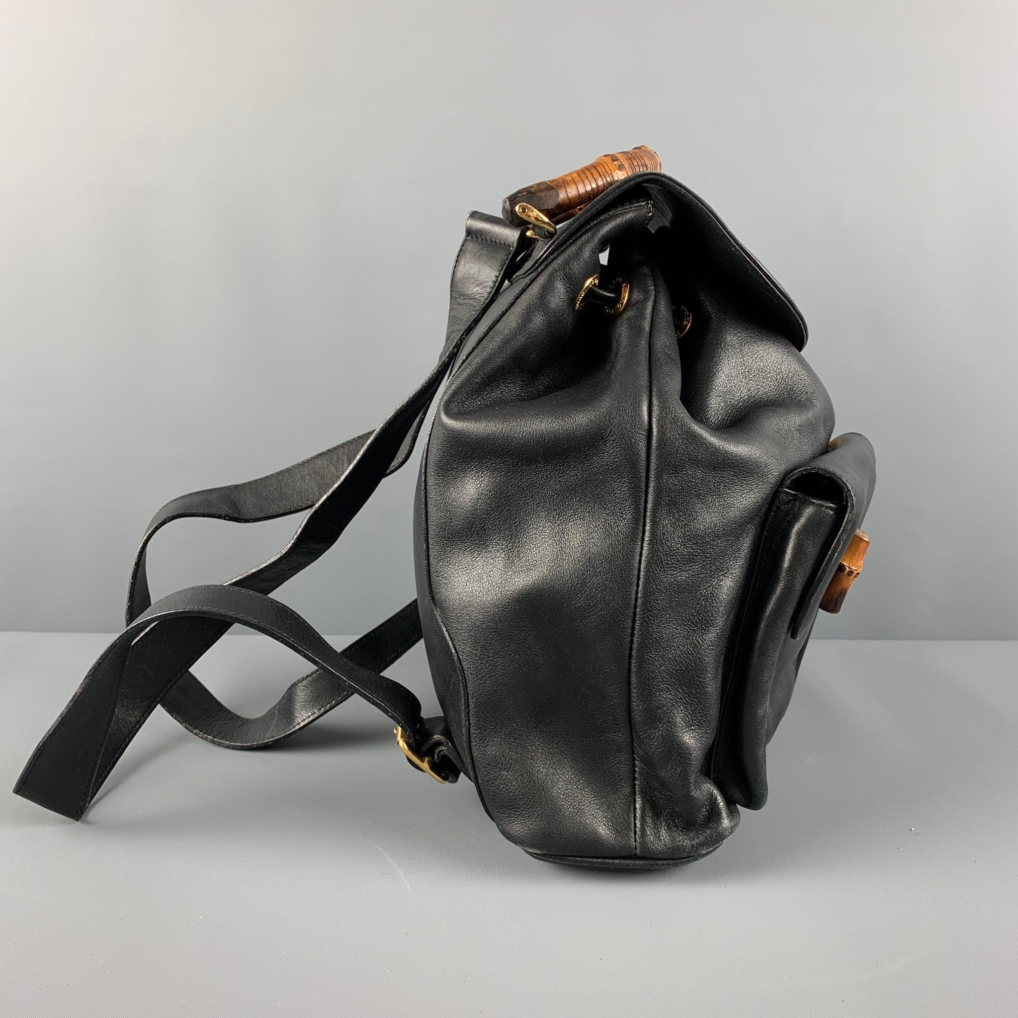 GUCCI Vintage backpack comes in a black leather featuring gold tone hardware, bamboo details, adjustable back strap, drawstring and buckle closures. Made in Italy.Very Good Pre- Owned Condition. Moderate Signs of Wear. 

Marked:   003.2058.0016