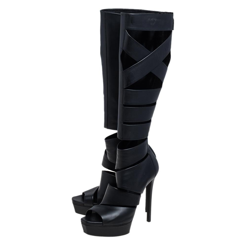 Luxurious and sophisticated, these knee-high boots from Gucci are a must-buy for the fashionable you. These black boots are crafted from leather and designed in a Gladiator style with cutouts, back zippers, and platforms with 14 cm