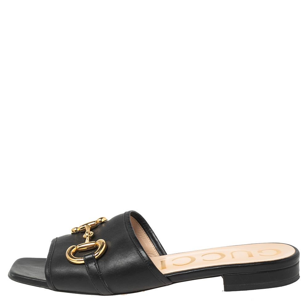 Experience both comfort and signature style with these slides from the House of Gucci. They are made from black leather with a gold-toned Horsebit embellishment perched on their vamps. They feature an easy slip-on style. Complement your casual