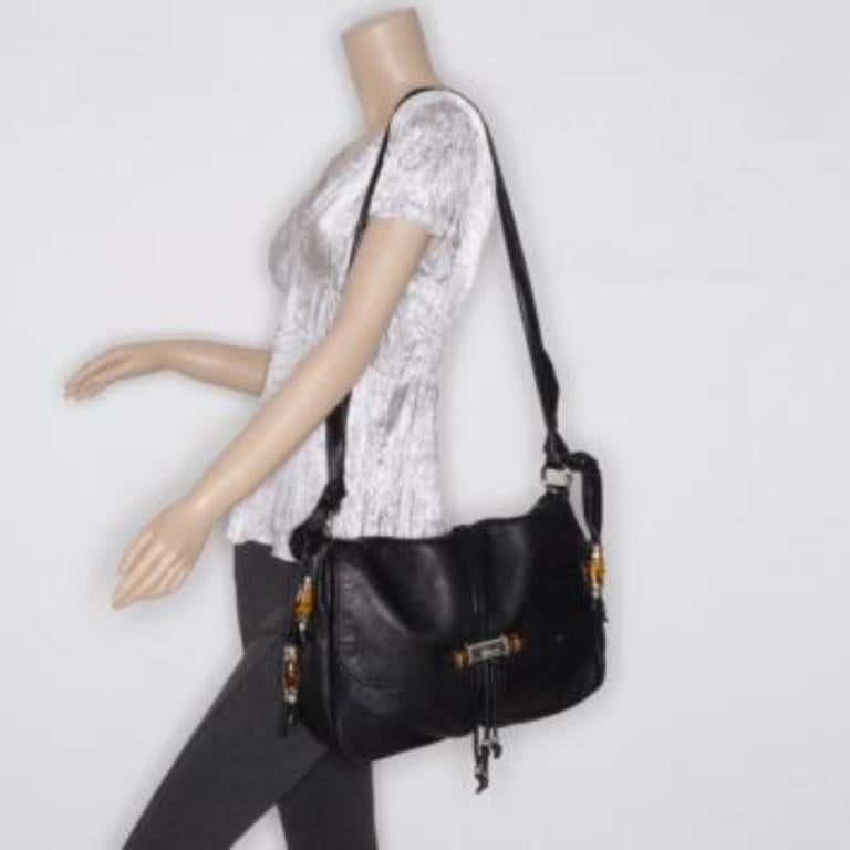 This Jungle messenger by Gucci is not your average black handbag. Crafted from supple black leather, it is accented with Gucci's signature bamboo accents, chic tassels and silver hardware. The interior is lined with Gucci monogram canvas, two