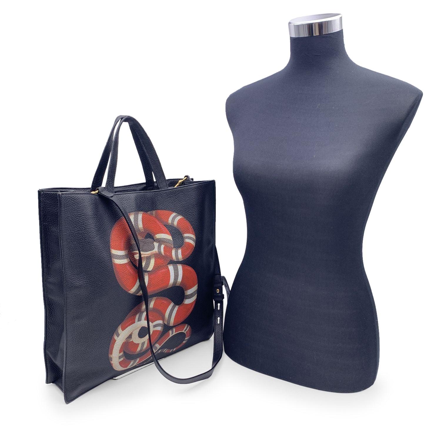 Beautiful Gucci black leather tote bag with Kingsnake print. Magnetic button closure on top. Double top carry handle. Cotton linen lining with 25 print. 2 side zip pocket inside. Made in Italy. The tote comes with a removable shoulder strap. 'GUCCI